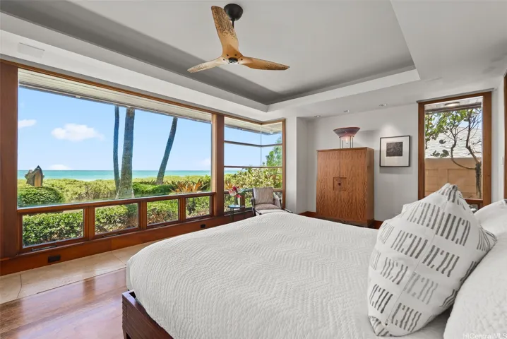 The primary bedroom is surrounded by windows capturing spectacular panoramic views of the beach and iconic sunrises. Electronic blinds provide privacy and darkness for peaceful night sleeping.