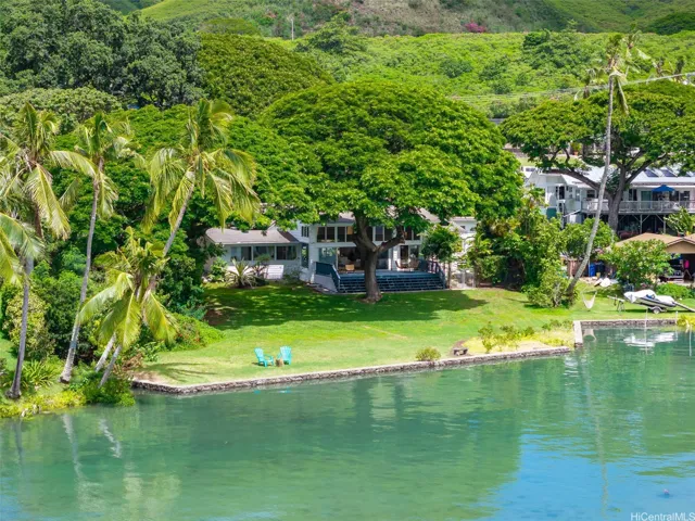 Expansive waterfront lawn framed by majestic Monkey Pod and mango trees.
