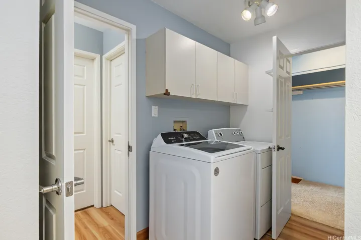 Full sized washer and dryer with lots of storage cabinetry above keeps the bathroom tidy.  All raised panel doors.