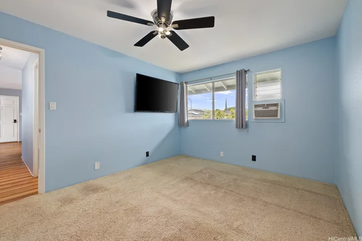 Calm color in primary bedroom, window covering and air conditioner included.  Ceiling fan to circulate air if needed.  (TV not included)