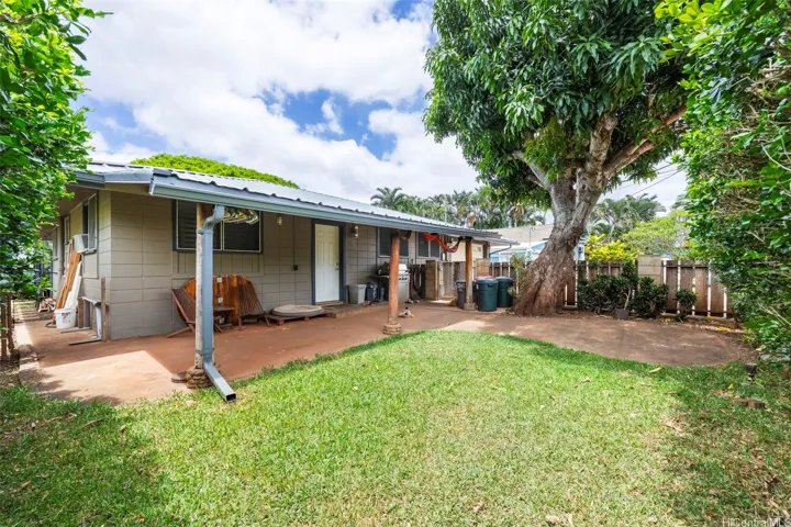 Tidy, fenced front yard with a mango tree f