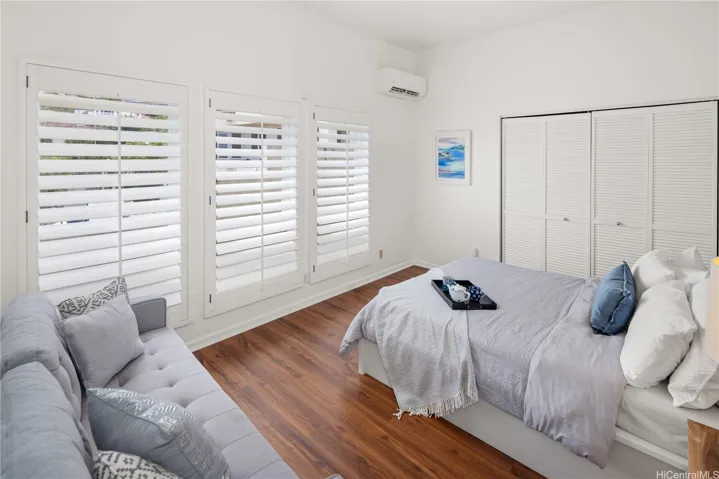 Bedroom on the main level includes a large walk-in closet, split AC, and pretty shutters.