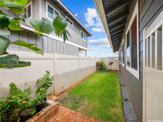 Gated side yard with rain gutters, landscaping and sprinkler system.