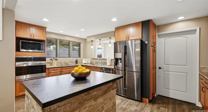 Chef's kitchen featuring stainless steel appliances, granite countertops, and a stone-accented center island.