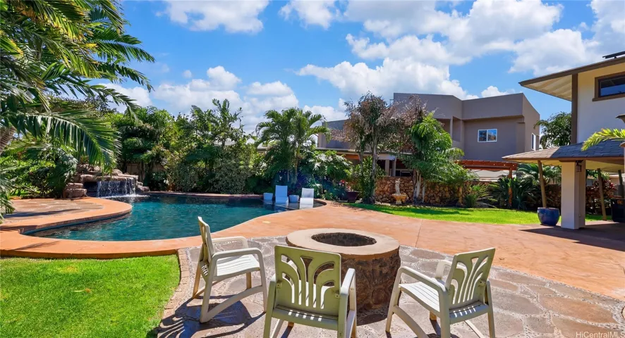 Custom outdoor entertainment area featuring a built-in stone fire pit right beside the pool.
