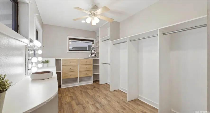 Massive custom walk-in closet and dressing room with built-in dressers, shelving, and a lighted vanity station.