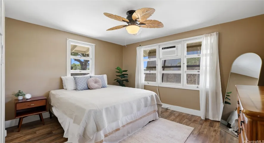 Main-level bedroom featuring a tropical leaf ceiling fan, window AC, and great natural light.