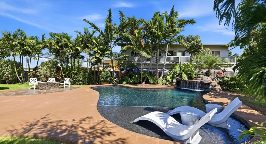 Resort-style in-ground pool featuring built-in ledge loungers and a relaxing rock waterfall.