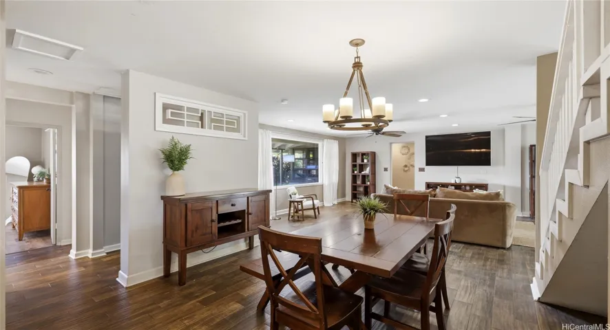 Open-concept dining area with a statement chandelier, matching wood trim, and a clear view into the main living space.