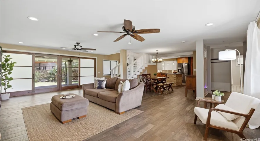 Open-concept living room featuring dual ceiling fans, modern flooring, and large sliding doors to the backyard.