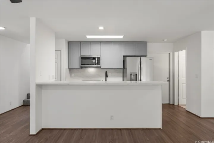 Open kitchen area with counter top seating and ample natural light