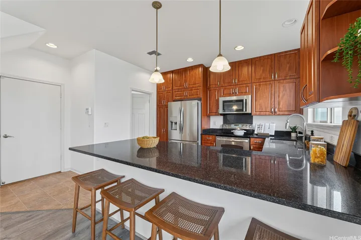 Contemporary kitchen with rich wood cabinets, pendant lighting, and a breakfast bar.