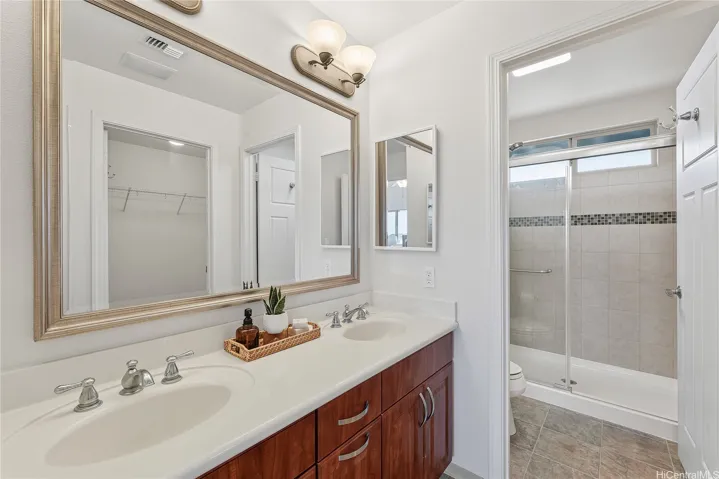 Bathroom with a double-sink vanity, large framed mirror, and tiled tub-shower combination.