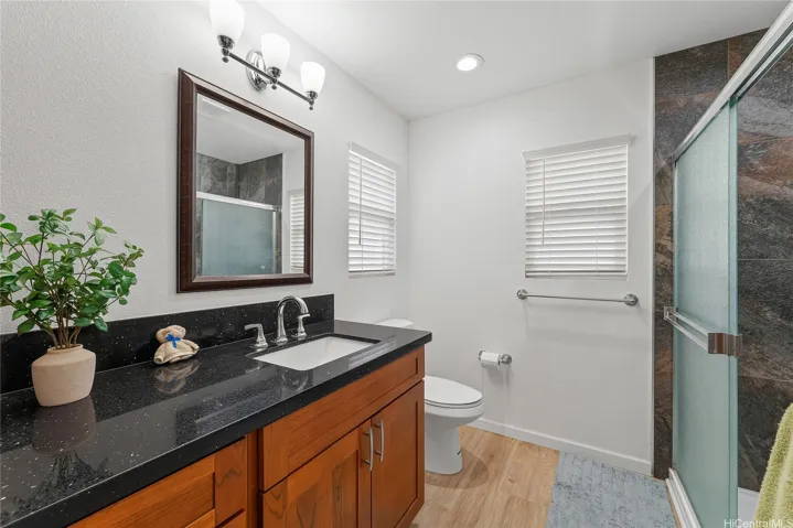 Modern bathroom with a wood vanity, large mirror, and glass-enclosed shower.