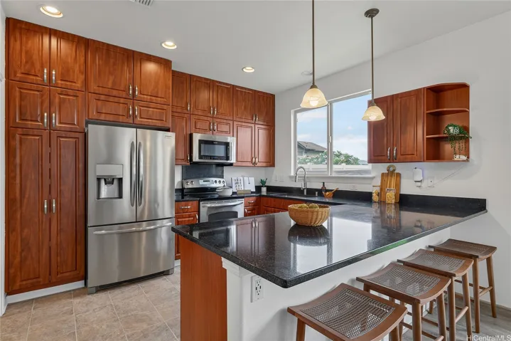 Kitchen from a different angle showcasing stainless steel appliances, generous cabinetry, and counter seating.