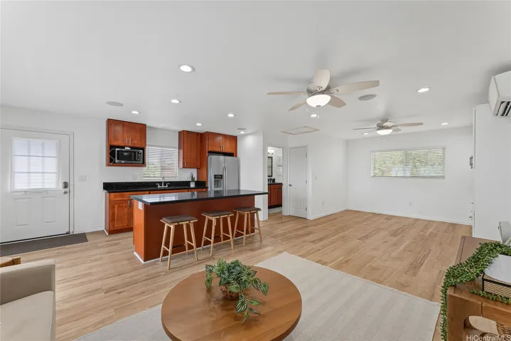 Open living space flowing into the kitchen, with wood flooring and a relaxed layout.