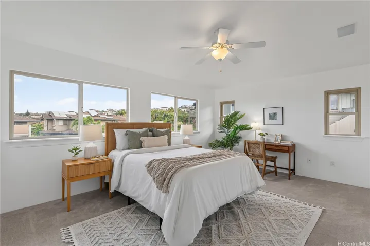 Spacious primary bedroom with multiple windows, ceiling fan, and a dedicated desk area.
