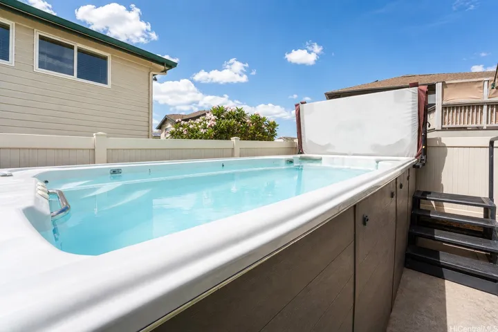 Large above-ground swim spa with surrounding privacy fencing.