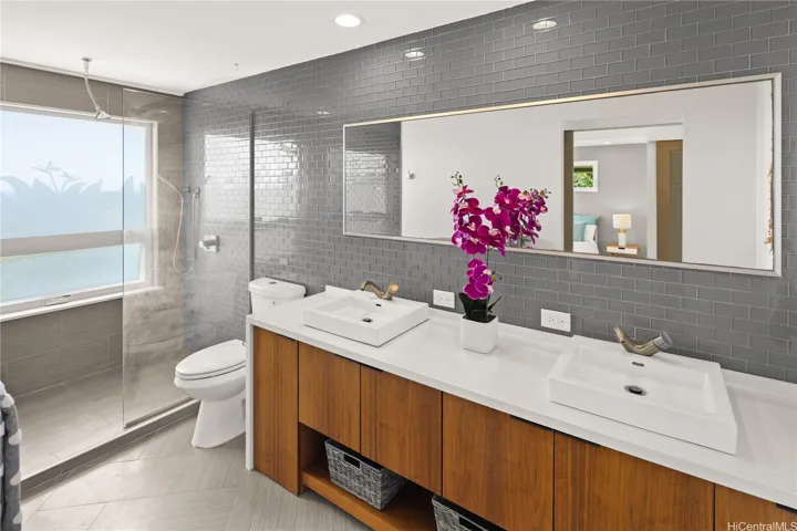 The Primary Suite includes this en-suite bathroom with dual sinks, large walk-in shower, and sleek tile walls and flooring.
