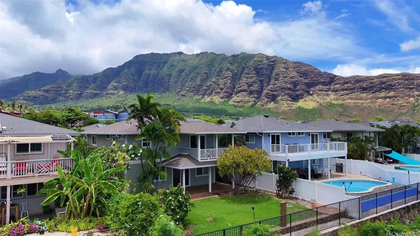 Rear exterior aerial view of the large open back yard against the backdrop of the Waianae range