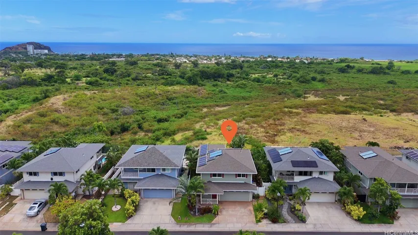 Front exterior aerial view of the island style home with a backdrop of Makaha Beach and the blue ocean