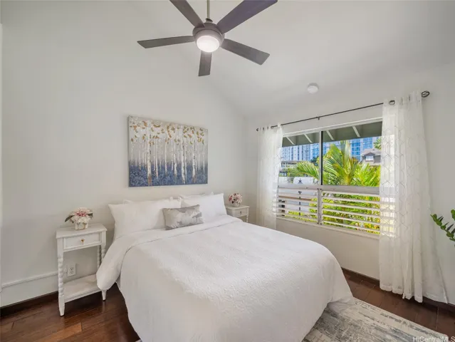 Spacious bedroom with high ceilings and lush green views.