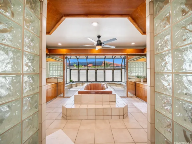Upstairs primary ensuite with dramatic glass block entry opens to a spacious bath retreat accented by warm wood details.