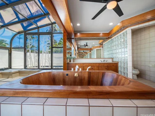 Oversized wooden soaking tub beneath expansive windows and sun room creates a relaxing, natural & spa inspired escape.