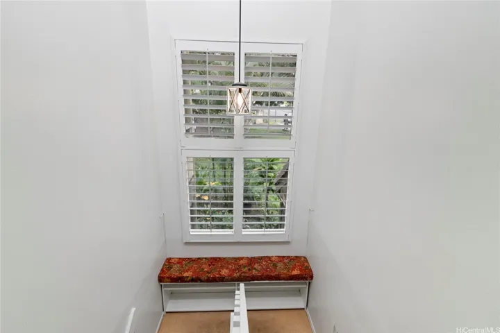 Bright staircase with plantation shutters with bench on the way upstairs.