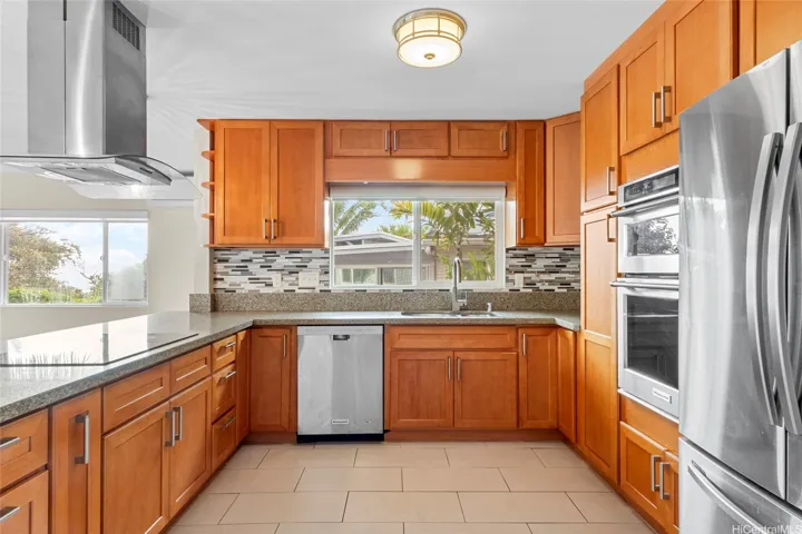 A cook's kitchen with ample counter and cupboard space, a venting hood, and stainless appliances including a double oven.