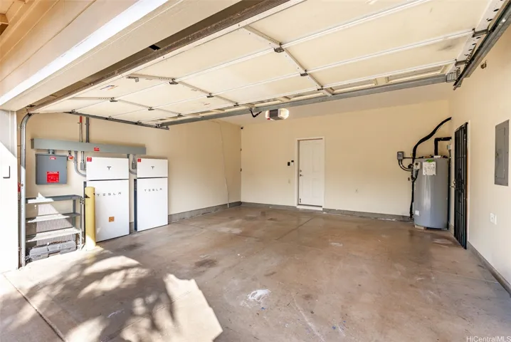 The enclosed two-car garage provides direct access to the home and includes the Tesla battery storage system and EV chargers.