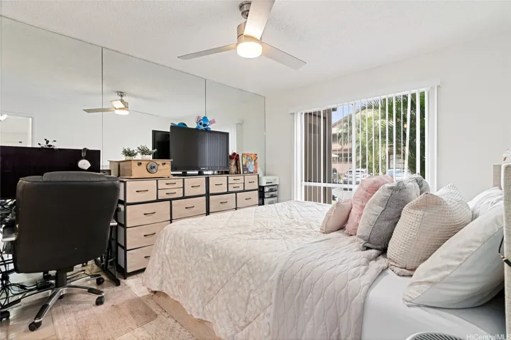 Generously sized primary bedroom featuring a full wall of mirrors that enhances the sense of space and light, along with ample closet space and the added convenience of an en-suite half bathroom.