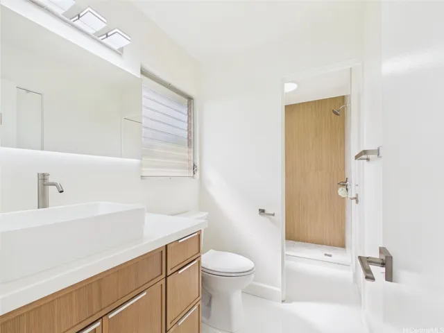 Renovated bath with quartz-top vanity, vessel sink, and backlit mirror
