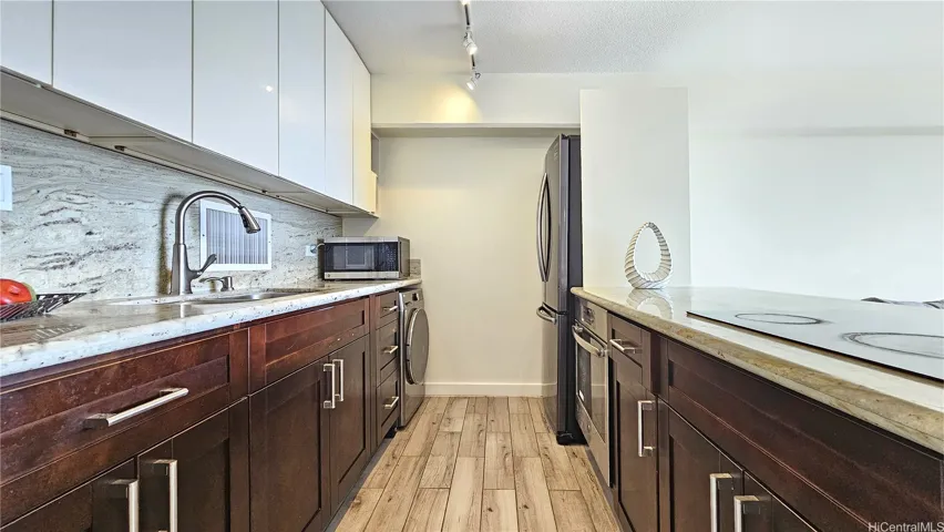 An open concept kitchen with newer stainless-steel appliances and granite countertops.