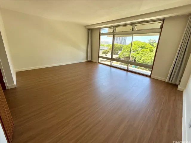 Large windows invite in abundant natural light while offering views of the lush Queen Emma Gardens and scenic Nuuanu surroundings.