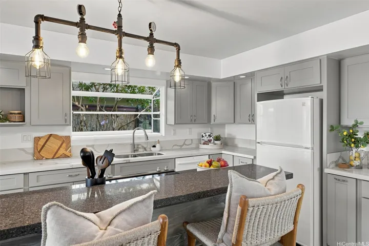 Ample counter space, extensive cabinetry, bright lighting, and solid surface countertops highlight this beautifully remodeled kitchen, which also features a charming bay window.