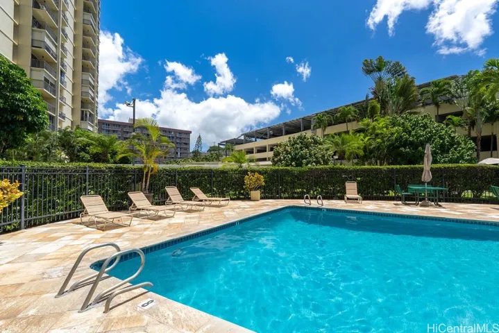 Community pool with lounge chairs and picnic tables.