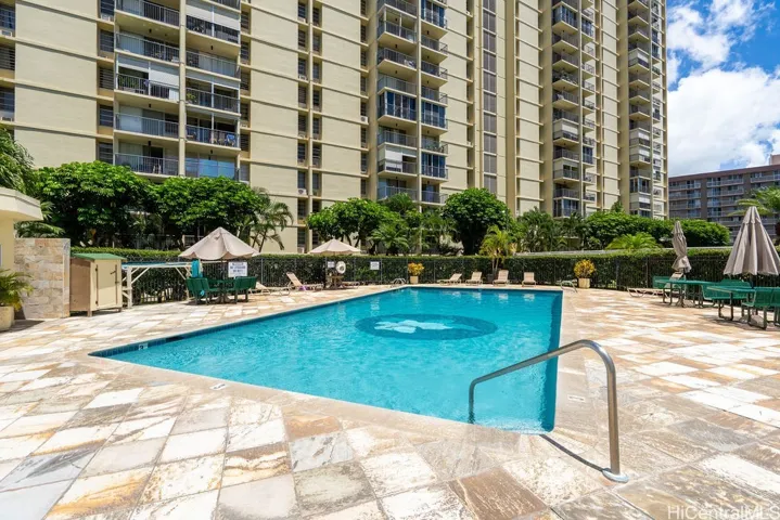 Large community pool with lounge chairs and picnic tables.