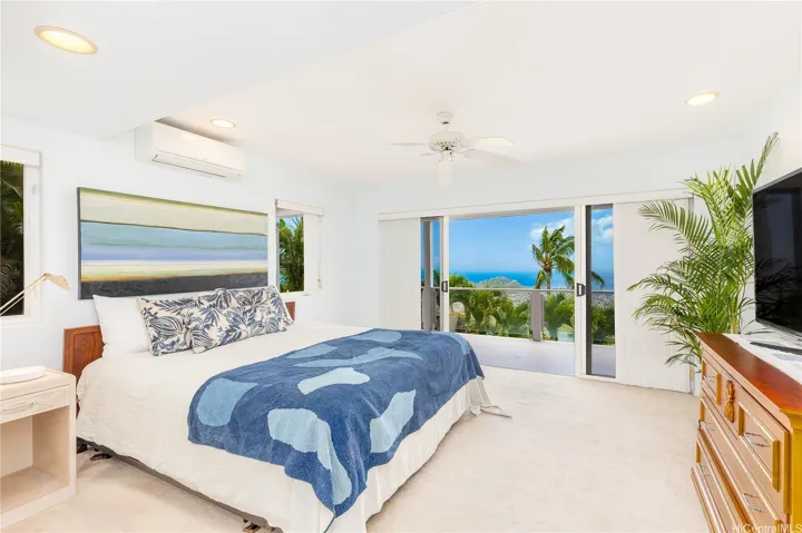 Spacious second bedroom with sliding doors opening to a covered wraparound deck, extending the living space outdoors.