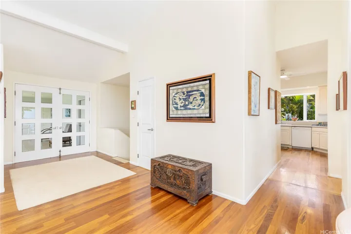 Elegant double-door entry conveniently positioned off the kitchen, with a staircase leading to the private downstairs bedrooms.