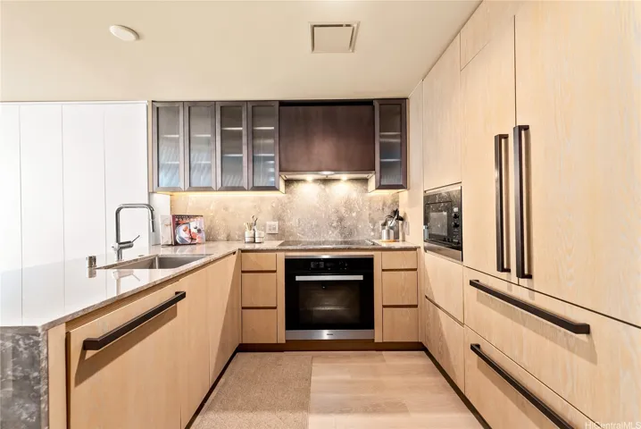 Kitchen with Miele Appliances, custom-designed European-style wood cabinetry with glass upper cabinets and a seamless soft-close mechanism, and Jerusalem Limestone countertops.