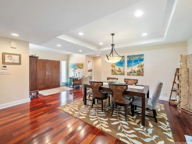 Elegant yet inviting, this formal dining area provides the perfect setting for everything from intimate family meals to special occasions. Rich hardwood flooring, a tray ceiling with recessed lighting, and a stylish centerpiece chandelier create a sophisticated ambiance, while the open-concept layout maintains a spacious and comfortable feel. Conveniently located adjacent to the main living areas, the dining space flows effortlessly throughout the home, making entertaining easy and enjoyable. Warm finishes and tasteful design elements enhance the welcoming atmosphere, offering a refined space to gather and create lasting memories.