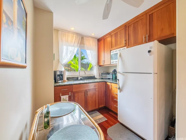 onveniently located between the guest bedroom and bathroom, this charming kitchenette offers added comfort and privacy for guests. Featuring rich wood cabinetry, granite countertops, a full-size refrigerator, microwave, sink, and dining nook, the space is both functional and inviting. A large window brings in natural light and tropical garden views, creating a bright, welcoming atmosphere.