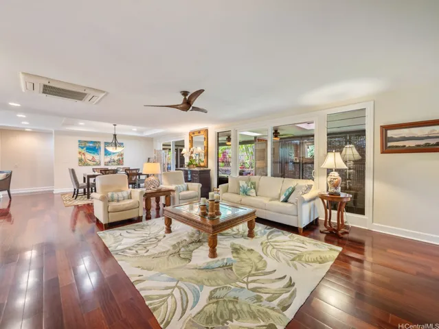 This spacious open-concept living and dining area offers a warm and welcoming atmosphere, enhanced by rich hardwood floors, recessed lighting, and contemporary finishes throughout. Large sliding glass doors invite natural light and provide seamless access to the covered lanai, creating the perfect indoor-outdoor flow for Hawaii living. The generous layout easily accommodates both comfortable seating and formal dining spaces, making it ideal for entertaining guests or relaxing with family. Thoughtfully designed with an airy feel and elegant touches, this inviting great room serves as the central gathering place of the home.
