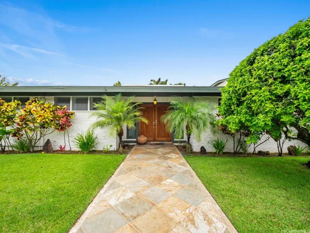 A welcoming stone walkway leads through beautifully manicured lawns and lush tropical landscaping to the home's impressive double-door entry. Framed by graceful palm trees and vibrant island foliage, the entrance creates a warm sense of arrival while showcasing the property's exceptional curb appeal. The expansive front yard and thoughtfully maintained gardens enhance both beauty and privacy, reflecting pride of ownership throughout.

The elegant wood entry doors and covered entryway provide a striking first impression, setting the stage for the spacious and beautifully designed interior. Surrounded by mature tropical plantings and a serene residential setting, this inviting entrance perfectly captures the charm and relaxed sophistication of island living.