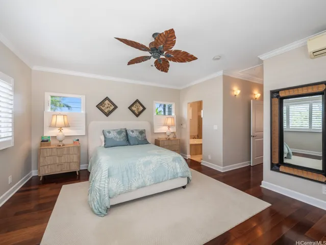 Privately situated on the upper level, this spacious primary bedroom suite is a serene retreat designed for comfort and relaxation. Rich hardwood flooring, expansive windows, and abundant natural light create a bright and inviting atmosphere, while tropical views enhance the peaceful setting. The generous layout easily accommodates a king-sized bedroom set with additional space for seating or a personal workspace. Ceiling fans and split-system air conditioning provide year-round comfort, making this a true sanctuary within the home.