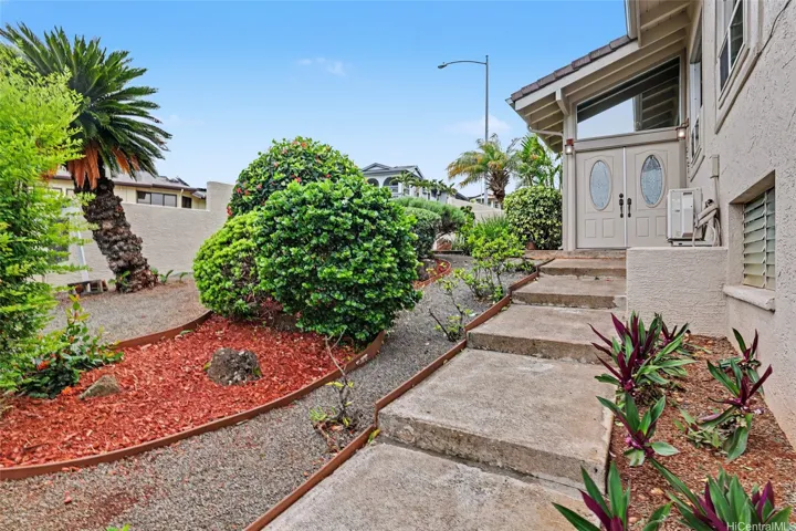 Lush tropical landscaping surrounds the property with colorful flowering plants, mature greenery, and a calamansi tree, creating a beautiful island setting.