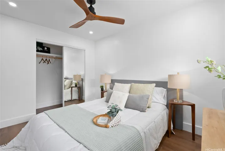 Comfortable second bedroom with a mirrored closet and ceiling fan.
