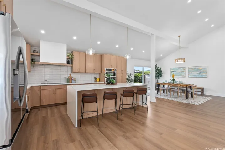 Beautifully designed kitchen featuring a stylish tile backsplash, waterfall island, and bar seating.
