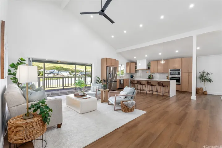 Bright, open-concept living and kitchen area featuring vaulted ceilings, warm luxury vinyl flooring, and seamless access to the spacious lanai.